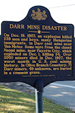 The plaque reads as follows: "On December 19, 1907, an explosion killed 239 men and boys, many Hungarian immigrants, in Darr coal mine near Van Meter. Some were from the closed Naomi mine near Fayette City, which exploded on Dec. 1, killing 34. Over 3000 miners died in Dec. 1907, the worst month in U. S. coal mining history. In Olive Branch Cemetery, 71 Darr miners, 49 unknown, are buried in a common grave."